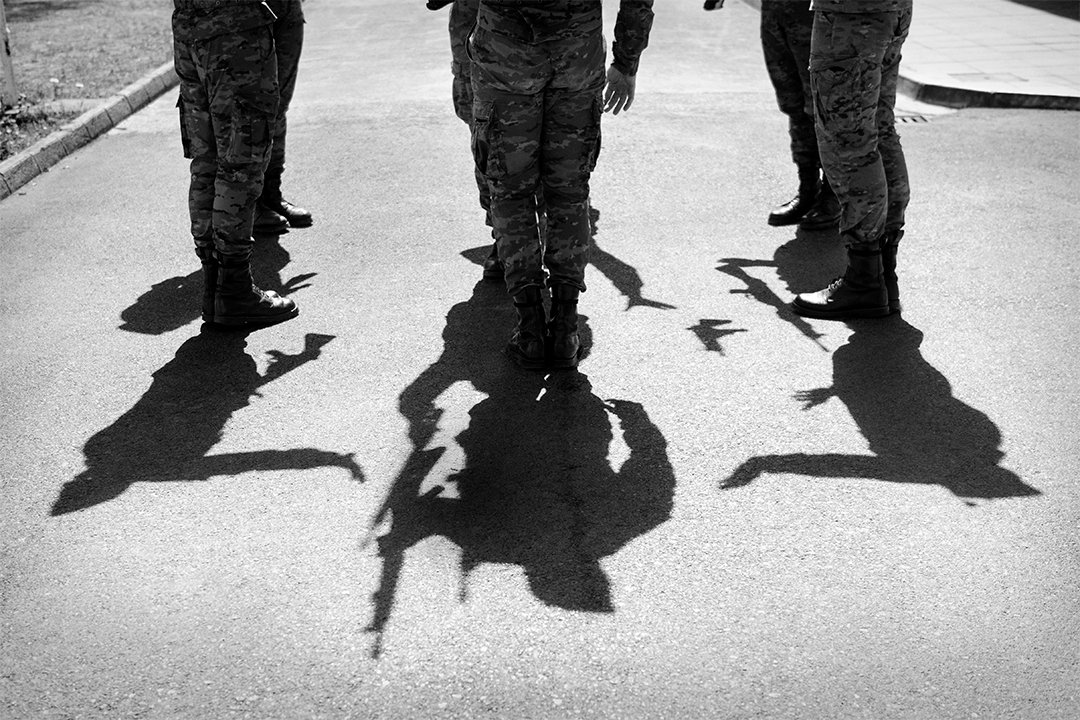 Service members’ boots and shadows on paving.